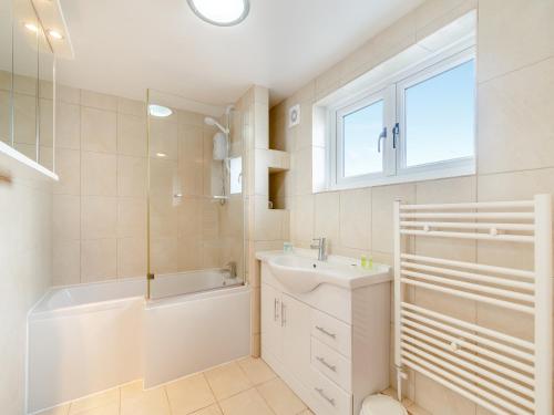 a white bathroom with a tub and a sink and a bath tubermott at Honeysuckle Cottage- Uk45594 in Verwick