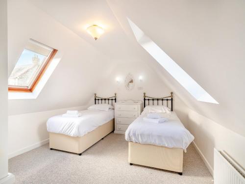 two twin beds in a attic bedroom with a window at Honeysuckle Cottage- Uk45594 in Verwick