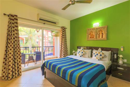 een groene slaapkamer met een bed en een balkon bij La Goa Villa - 4BHK, Baga in Baga