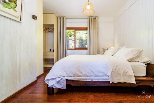 a bedroom with a large white bed and a window at Horizon Hill Villa in Pirae