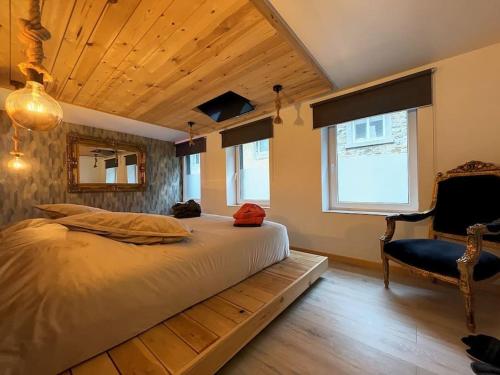 ein Schlafzimmer mit einem großen Bett und einem Stuhl in der Unterkunft L'ancre céleste in Aywaille