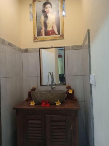 La salle de bains est pourvue d'un lavabo et d'un miroir. dans l'établissement Swastika Guest House Ubud, à Ubud