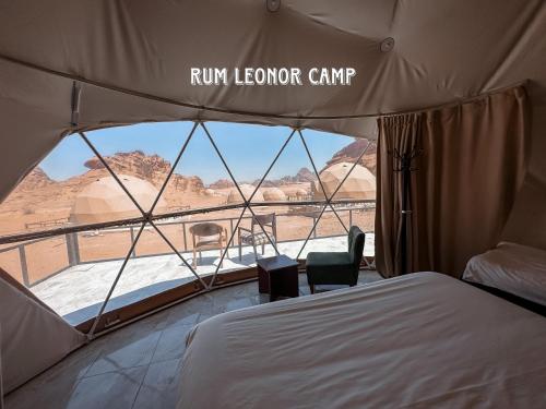 a tent with a bed and a view of the desert at RUM LEONOR CAMP in Wadi Rum