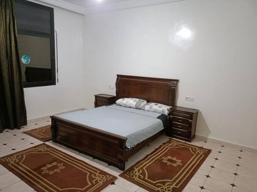 Villa à la décoration marocaine في الرباط: غرفة نوم بسرير خشبي كبير وسجادتين