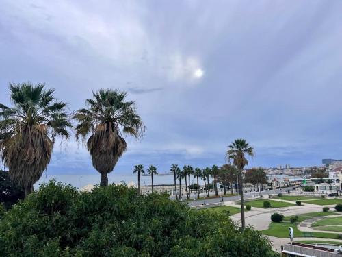 Elle offre une vue sur un parc planté de palmiers et l'océan. dans l'établissement Estoril - Bay view apartment, à Estoril