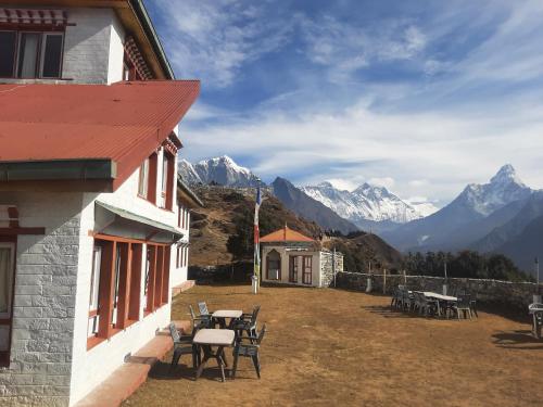 a building with tables and chairs and mountains in the background at Sherpa Panorama Hotels in Khumjung