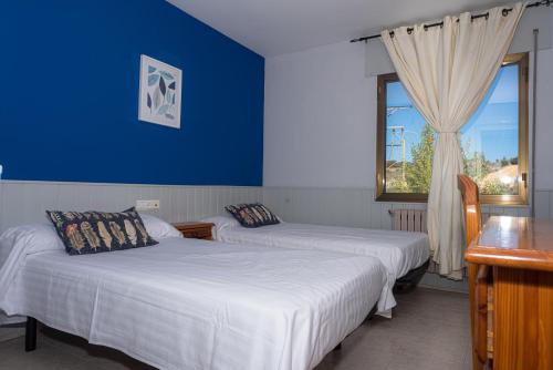 two beds in a room with a blue wall at Hostal Venta de Valcorba in Soria