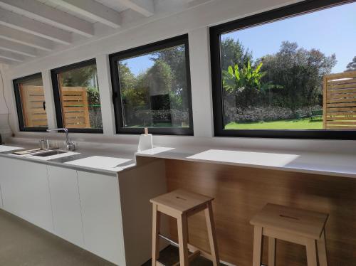 a kitchen with three windows and a counter with stools at Casa Playas Costa Quebrada in Santa Cruz de Bezana
