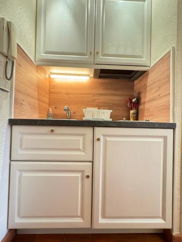 une cuisine avec des armoires blanches et un évier dans l'établissement Studio dans résidence, piscine lagon, tennis et aire de jeux, à Fréjus