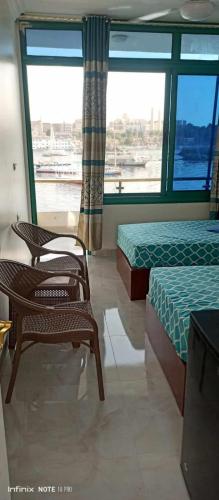 a room with two beds and a chair and a window at El-amin Guest House in Aswan