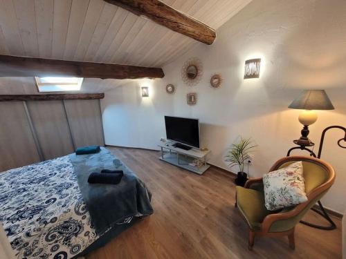 - une chambre avec un lit, une télévision et une chaise dans l'établissement Maison de Village en pierres, à Le Poët