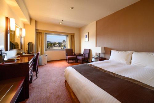 福山市にある福山ニューキャッスルホテルのベッドとデスクが備わるホテルルームです。