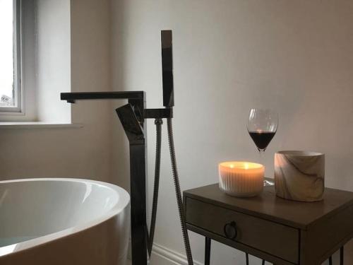 a bathroom with a bath tub and a glass of wine at The Penthouse in Windermere in Windermere