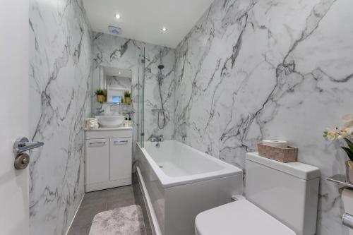 Baño blanco con aseo blanco y lavamanos en Three-Bedroom Bliss in London Town, en Londres