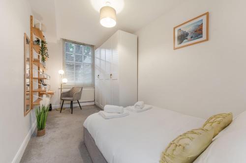 Un dormitorio blanco con 2 camas y una silla en Three-Bedroom Bliss in London Town, en Londres