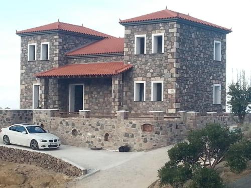 a white car parked in front of a stone house at Molivos Castleview Luxury Villa with private parking in Mythimna