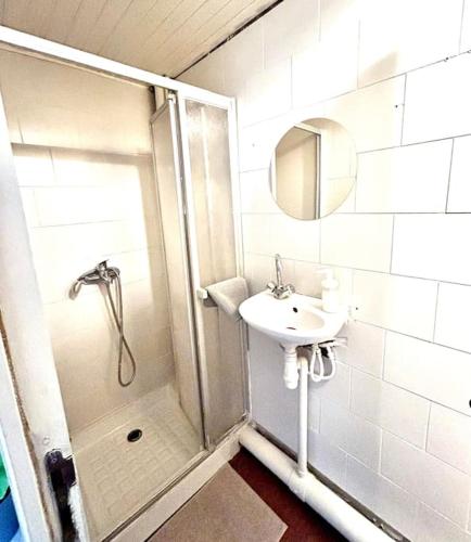La salle de bains blanche est pourvue d'une douche et d'un lavabo. dans l'établissement Le Cabanon à Pépé, aux Goudes, à Marseille