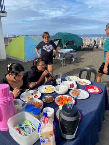 a group of people sitting around a table with food at CFAX Beach House in Campo