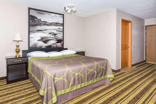a hotel room with a bed and a painting on the wall at Super 8 by Wyndham Rock Springs in Rock Springs