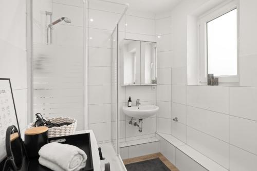 ein weißes Bad mit einem Waschbecken und einer Dusche in der Unterkunft SHINY HOMES - Kitchen - Free Parking - Netflix in Bielefeld