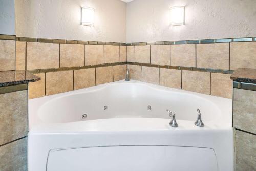 a bath tub with two faucets in a bathroom at Ramada by Wyndham West Atlantic City in West Atlantic City