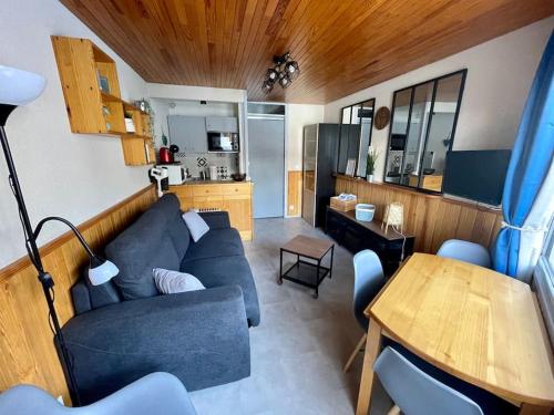 ein Wohnzimmer mit einem blauen Sofa und einem Tisch in der Unterkunft Chaleureux studio à 150m du Point Show in Vars
