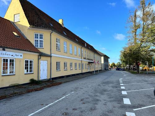 une rue vide devant un bâtiment jaune dans l'établissement Frederiksværk Hotel, à Frederiksværk
