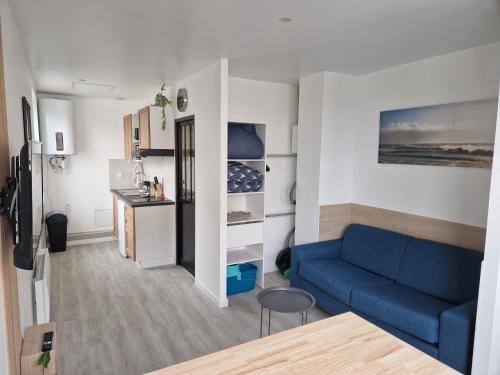 un salon avec un canapé bleu et une cuisine dans l'établissement Beau studio 24m2 près de Airbus, à Montoir-de-Bretagne