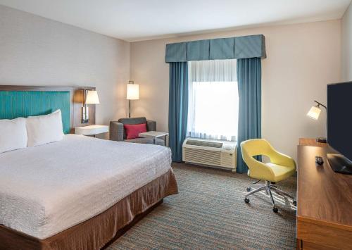 een hotelkamer met een bed, een stoel en een raam bij Hampton Inn & Suites Omaha Southwest-La Vista in La Vista