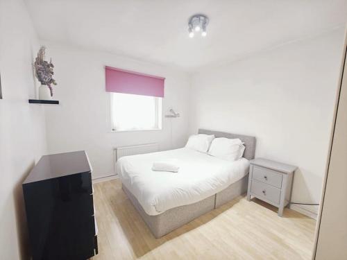 a white bedroom with a bed and a window at City Airport Apartment in London