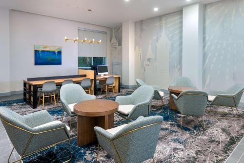 a waiting room with chairs and a table and a desk at Hyatt House Orlando Airport in Orlando