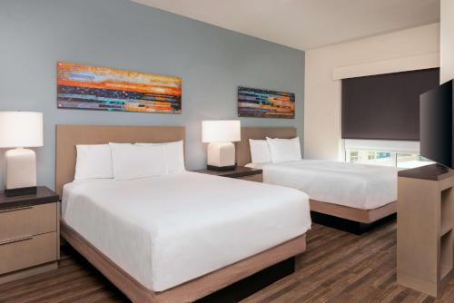 a hotel room with two beds and a flat screen tv at Hyatt House Orlando Airport in Orlando