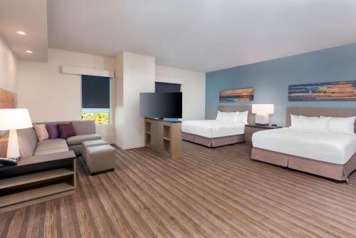 オーランドにあるHyatt House Orlando Airportのベッド2台とソファが備わるホテルルームです。