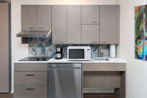 a kitchen with wooden cabinets and a white microwave at Hyatt House Orlando Airport in Orlando