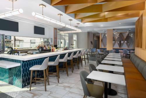 a restaurant with a bar and tables and chairs at Hyatt House Orlando Airport in Orlando