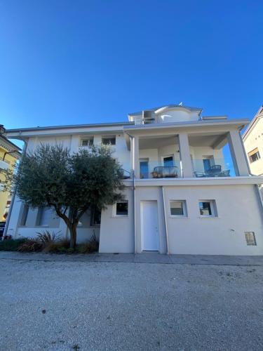 a white building with a tree in front of it at Kalé in Pordenone
