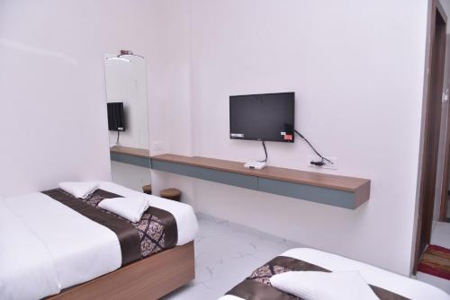 a room with two beds and a tv on a wall at Hotel D Square in Shirdi