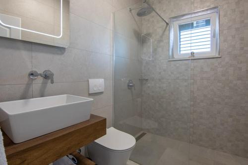 La salle de bains est pourvue de toilettes, d'un lavabo et d'une douche. dans l'établissement Ferienhaus Luisa Insel Brac - Kamin, Pool, Grill, Olivengrundstück, à Pučišća