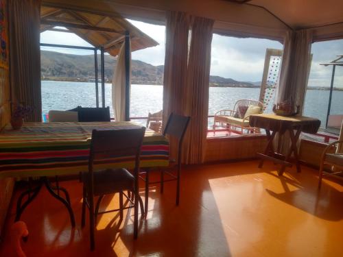 a dining room with a table and a view of the water at Uros Titicaca Ayni lodge in Puno
