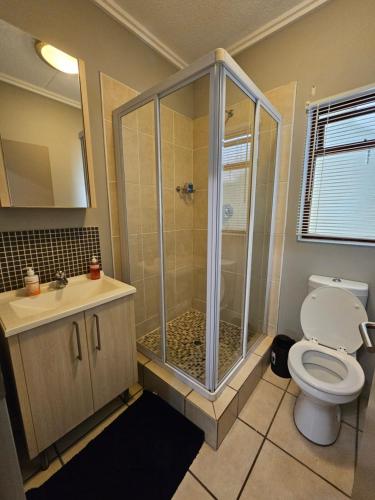 a bathroom with a shower and a toilet and a sink at Tevin Nest in Sandton