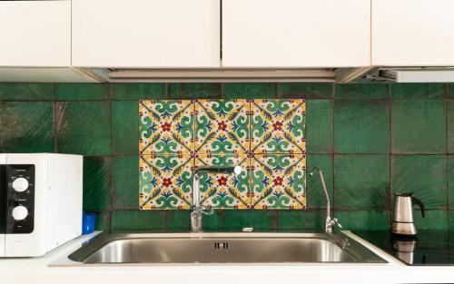 a kitchen with a sink and a green tiled wall at La Masa Apartment in Palermo