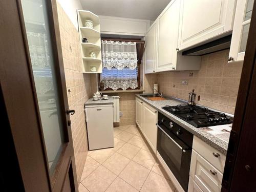 una piccola cucina con armadietti bianchi e piano cottura di Bardo Escape a Bardonecchia