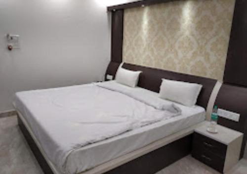 um quarto com uma cama grande e lençóis brancos em Maa Jagdamba Palace Bihar em Samastīpur