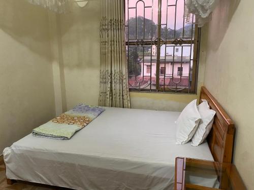a small bedroom with a bed with a window at Nhà nghỉ Minh Hạnh in Hoàng Ngà