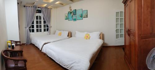 2 Betten in einem Zimmer mit weißen Wänden und Holzböden in der Unterkunft Nhà Xanh Bơ in Da Lat