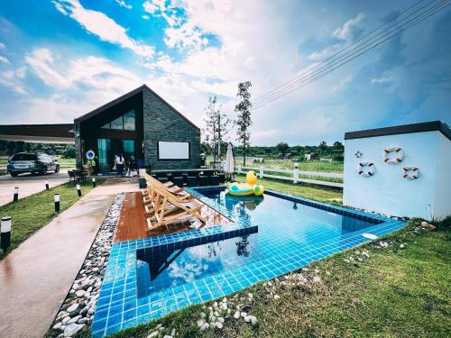 ein Haus mit einem Pool in der Mitte eines Gartens in der Unterkunft บ้านไออุ่น เขื่อนไม้เต็ง in Ban Na Thom