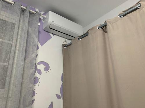 a bathroom with a shower curtain and a air conditioner at Studio La Félicité in Le Moule