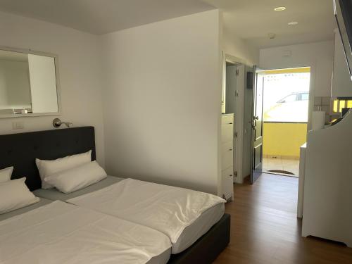 a bedroom with a white bed with a black headboard at Apartamento con piscina climatizada y vista al mar in San Bartolomé de Tirajana