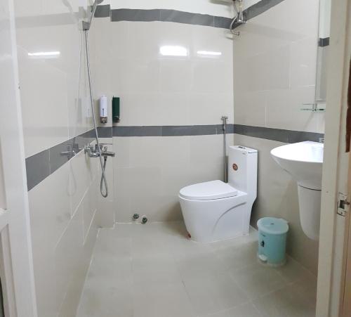 ein weißes Bad mit einem WC und einem Waschbecken in der Unterkunft Nhà Xanh Bơ in Da Lat