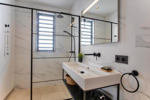 een witte badkamer met een wastafel en een douche bij Zon&zo Luxurious Apartment in Jan Thiel in Jan Thiel